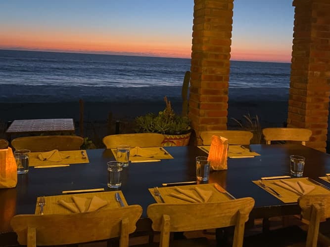 A dinner table set beside the ocean at dusk